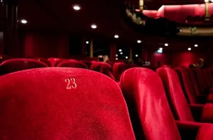 Close-up of plush red theatre seats—row 23—symbolising empty venues preparing for a post-pandemic ‘new normal’ with safer, digital ticketing.